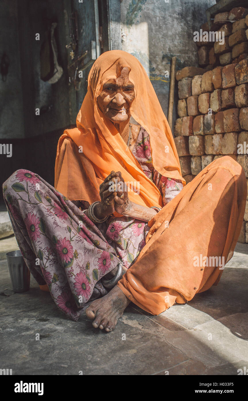 Région GODWAR, INDE - 13 février 2015 : personnes âgées femme indienne en sari avec tête couverte est assis dans la porte de la maison. Post-traités Banque D'Images