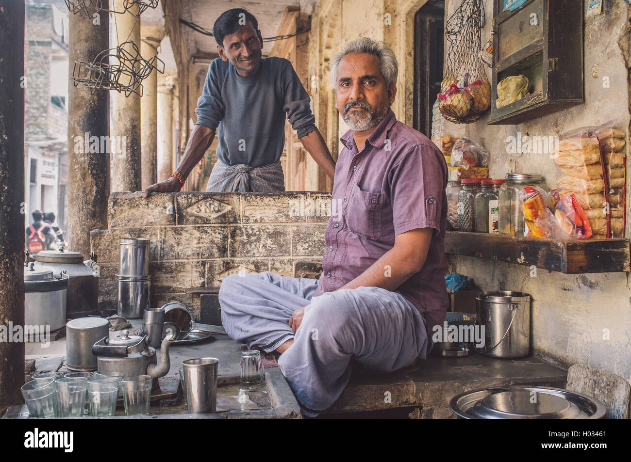 VARANASI, INDE - 21 février 2015 : vendeur de rue, la vente de thé laiteux se trouve dans shop alors que charpentier voisins est à côté de lui Banque D'Images