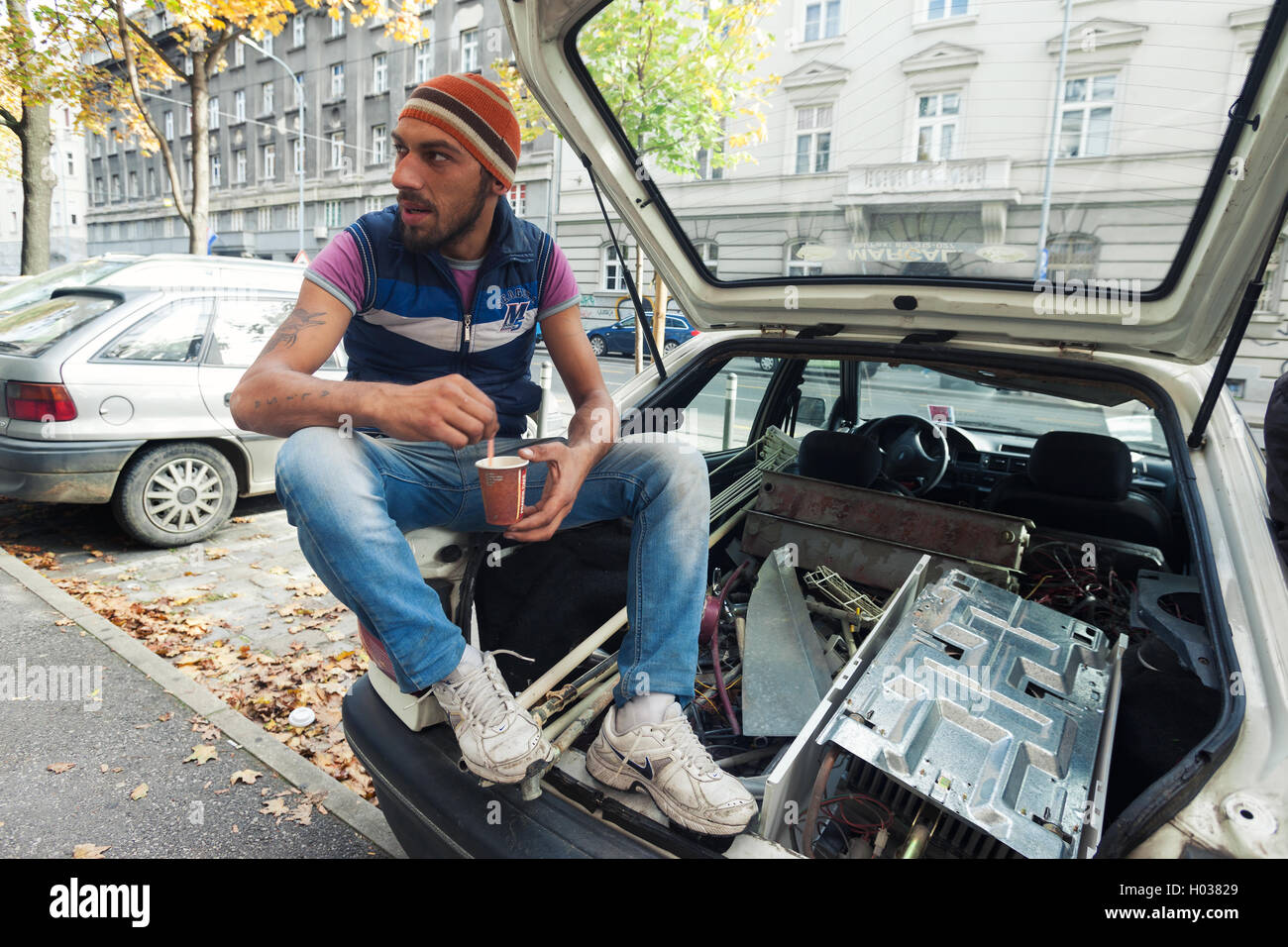 ZAGREB, CROATIE - le 17 octobre 2013 jeune Rom : boire du café à l'arrière d'une voiture remplie d'ordures ménagères. Banque D'Images