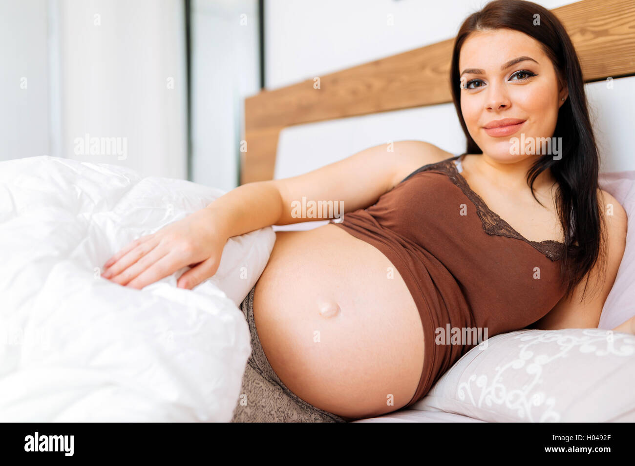 Portrait de femme enceinte belle positive au lit Banque D'Images