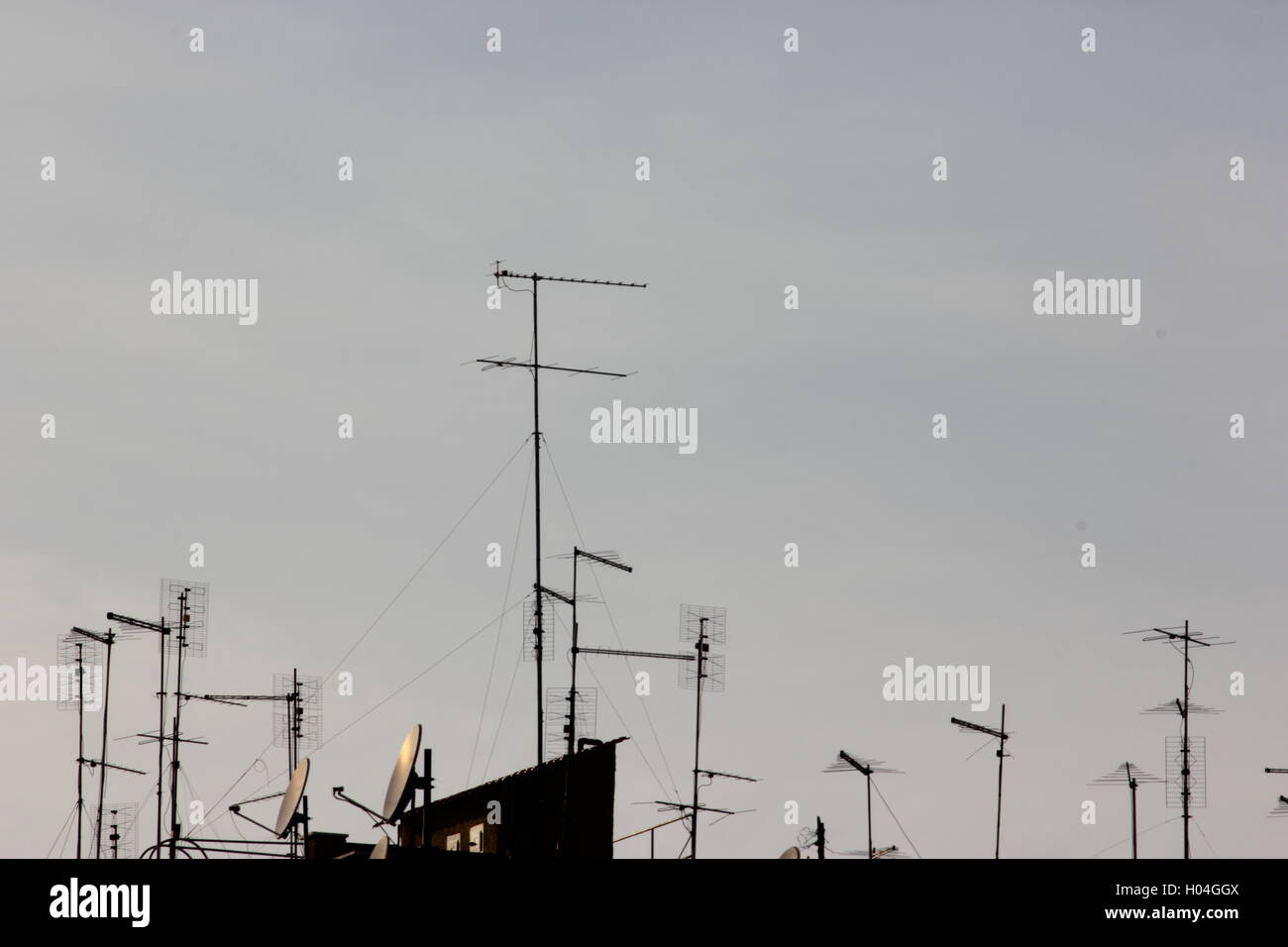 Antennes, antennes de télévision et paraboles sur toit avec ciel bleu clair Banque D'Images