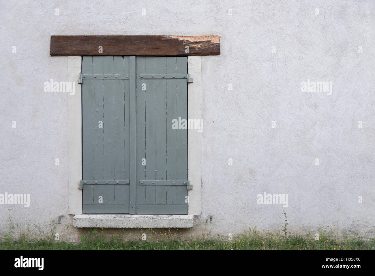 Fenêtre avec volets sur un chalet. Volets turquoise pâle. Mur de pierre blanche. L'espace négatif au côté droit. Paisible. Banque D'Images