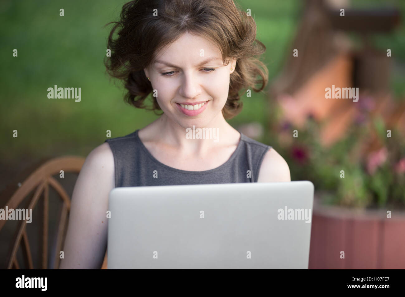 Portrait Portrait of happy smiling belle jeune femme assis sur un banc dans la rue en été, à l'aide d'un ordinateur portable, à la recherche Banque D'Images