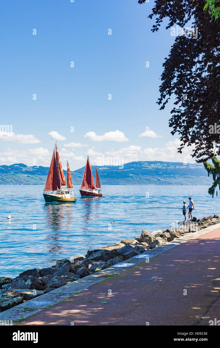 Couple la pêche au large de la promenade d'Evian comme des bateaux à voile traditionnels rendez-vous sur le lac de Genève, à Évian-les-Bains, France Banque D'Images