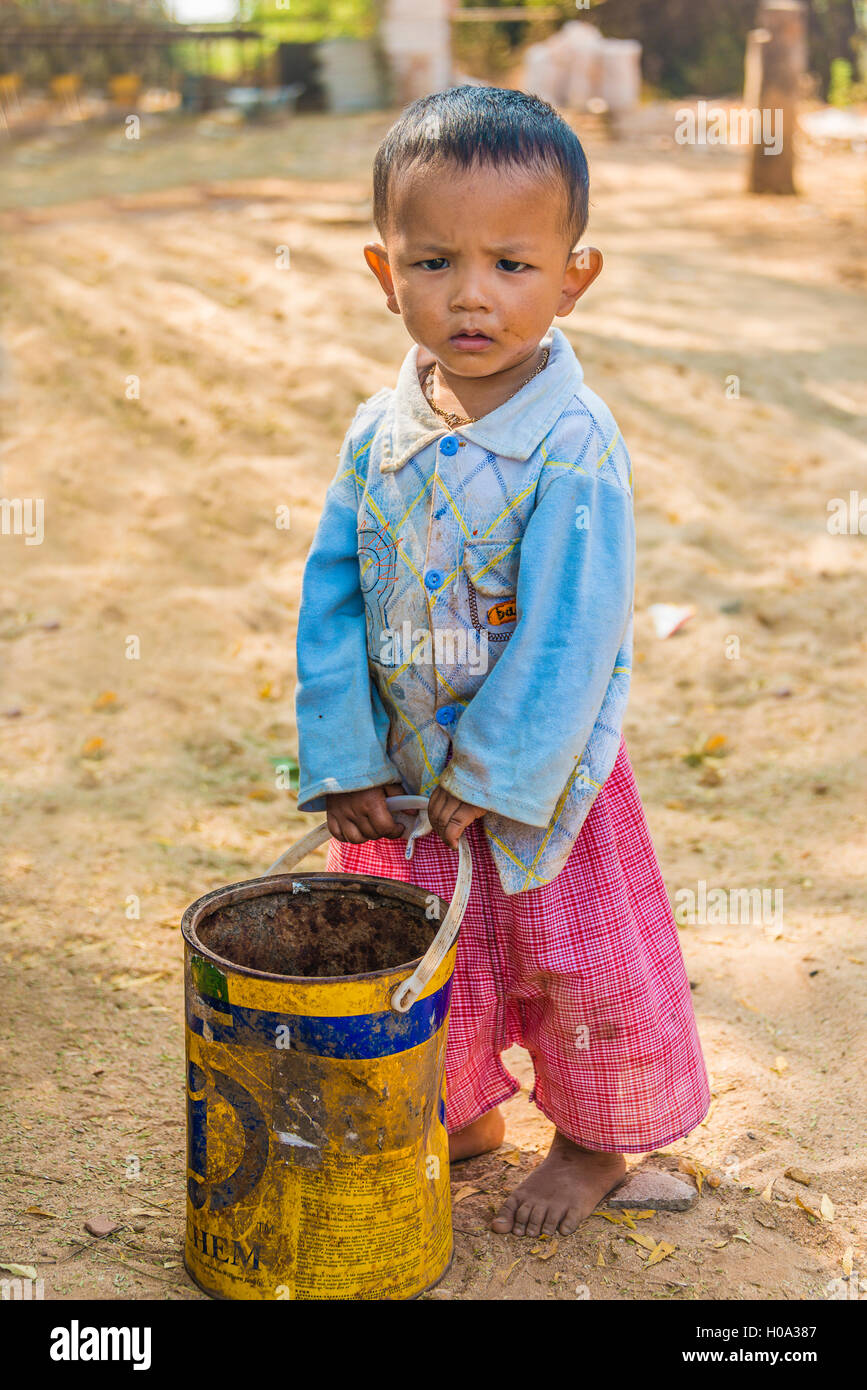 Enfant, garçon local avec un vieux seau, Bagan, Mandalay, Myanmar Région Banque D'Images