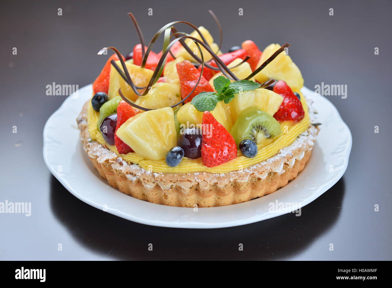 Gâteau de fruit avec ananas Fraise kiwi raisin on white plate in restaurant Banque D'Images