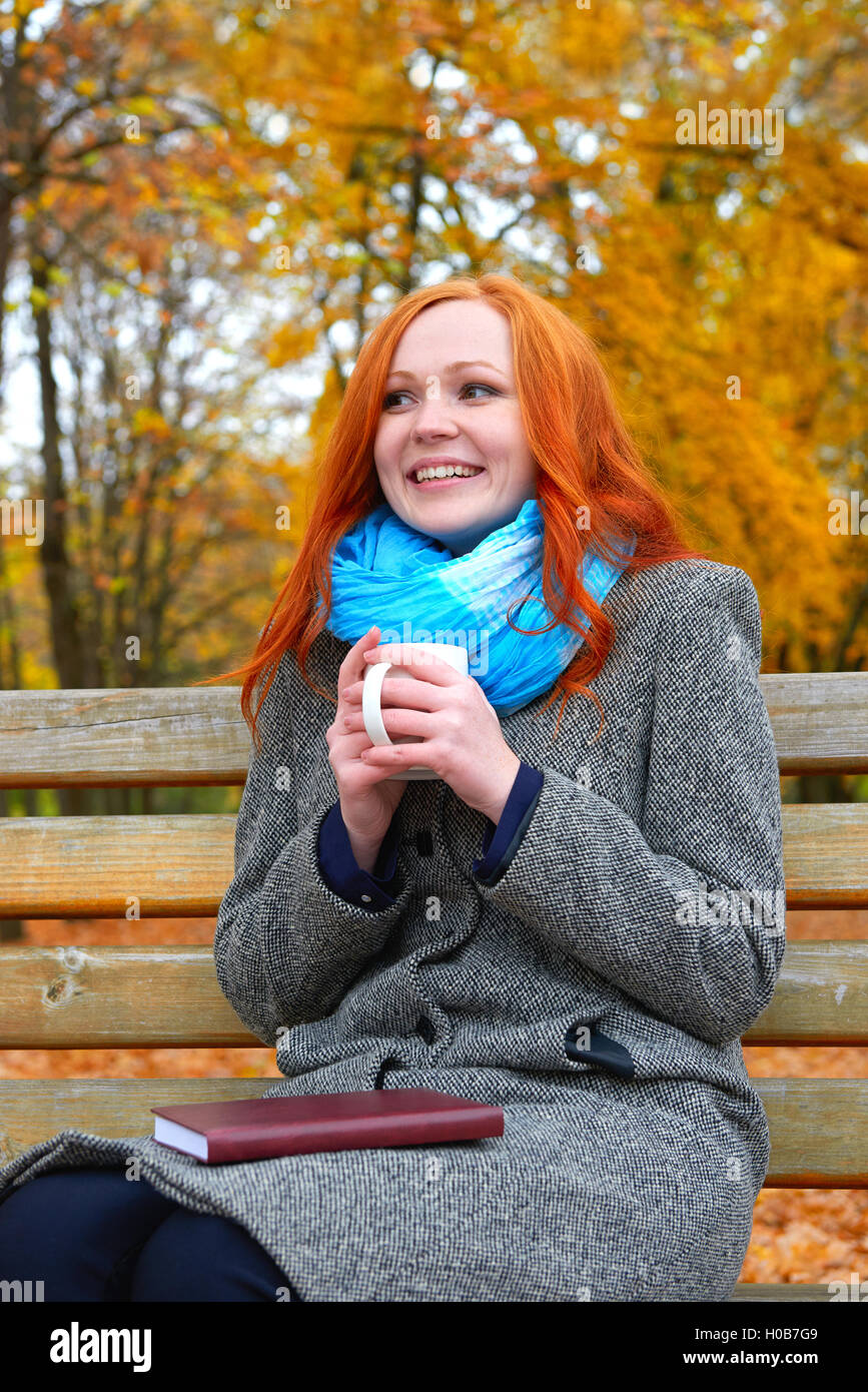 Fille avec tasse des mains chaudes en jaune du parc de la ville, saison d'automne Banque D'Images