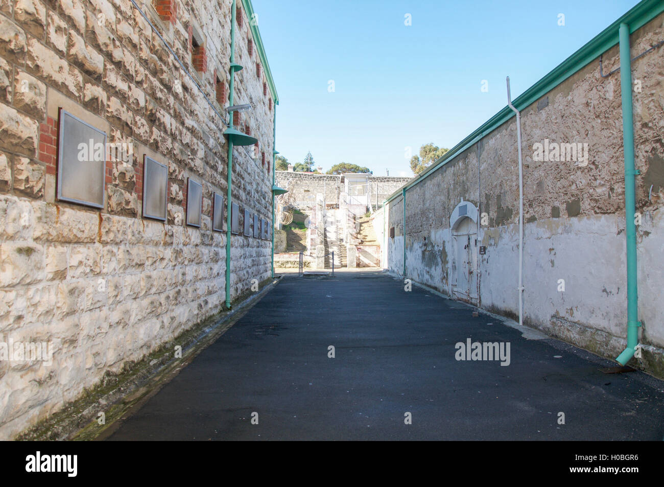 Zone de passage à travers les murs en brique calcaire à la prison de Fremantle sous un ciel bleu clair à Fremantle, Australie occidentale. Banque D'Images