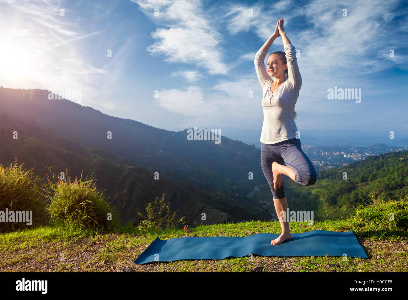 Woman in yoga asana Vrikshasana posture de l'arbre dans les montagnes à l'extérieur Banque D'Images