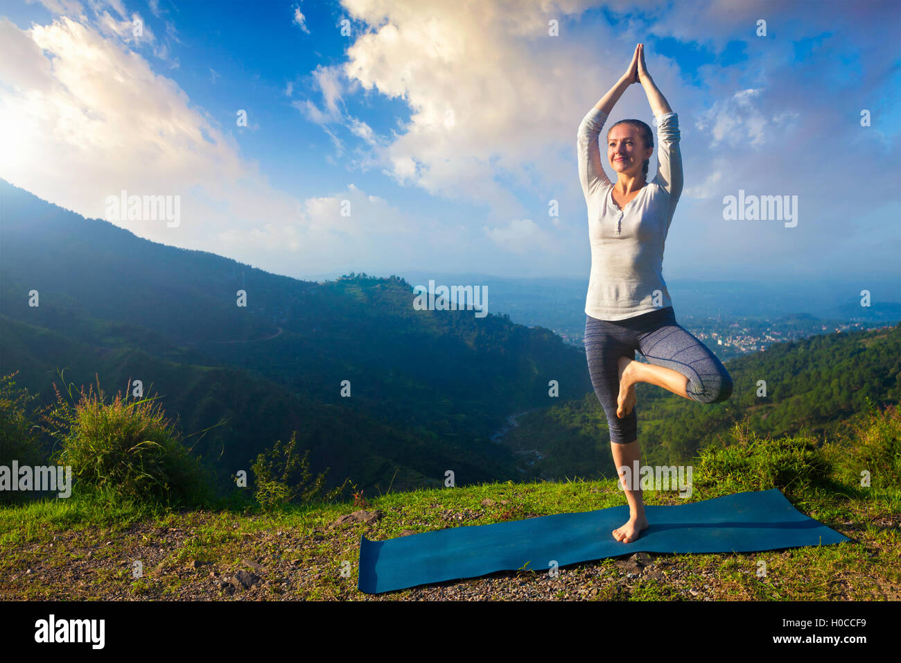 Woman in yoga asana Vrikshasana posture de l'arbre dans les montagnes à l'extérieur Banque D'Images