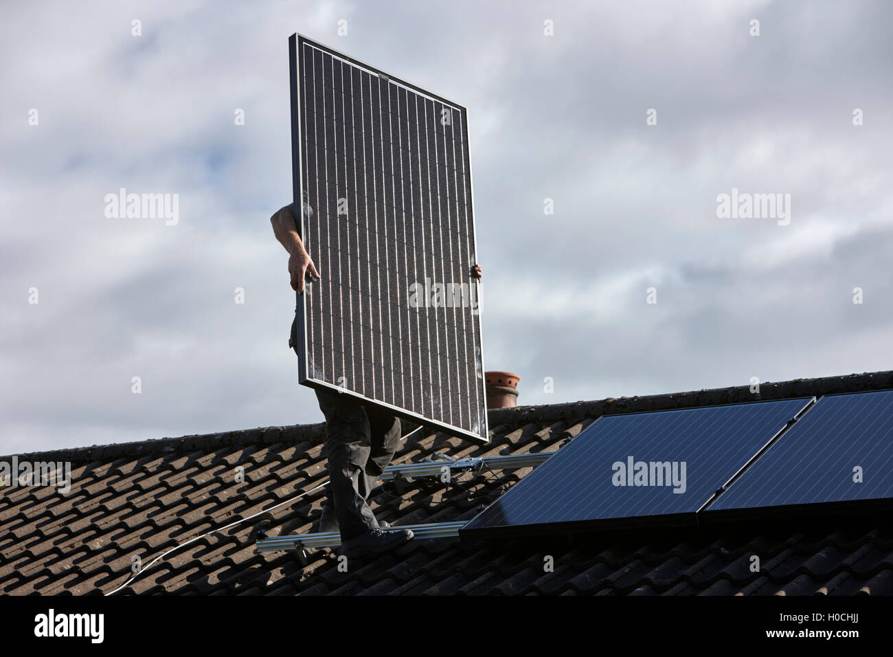 L'installation de panneau solaire sur le toit de l'homme dans une installation de panneaux solaires domestiques au Royaume-Uni Banque D'Images