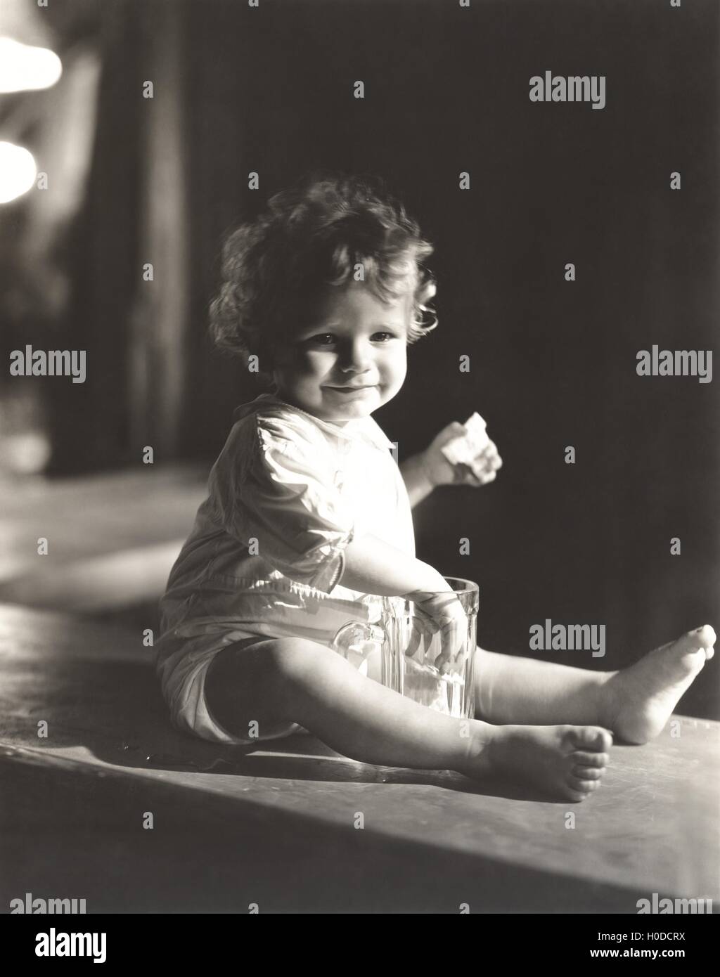 Baby Boy avec sa main dans un verre de bière Banque D'Images