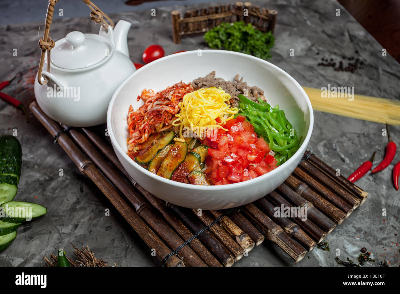 Nouilles coréen avec le kimchi, les tomates, le piment dans un bol blanc sur le plateau en bambou avec plateau pot Banque D'Images