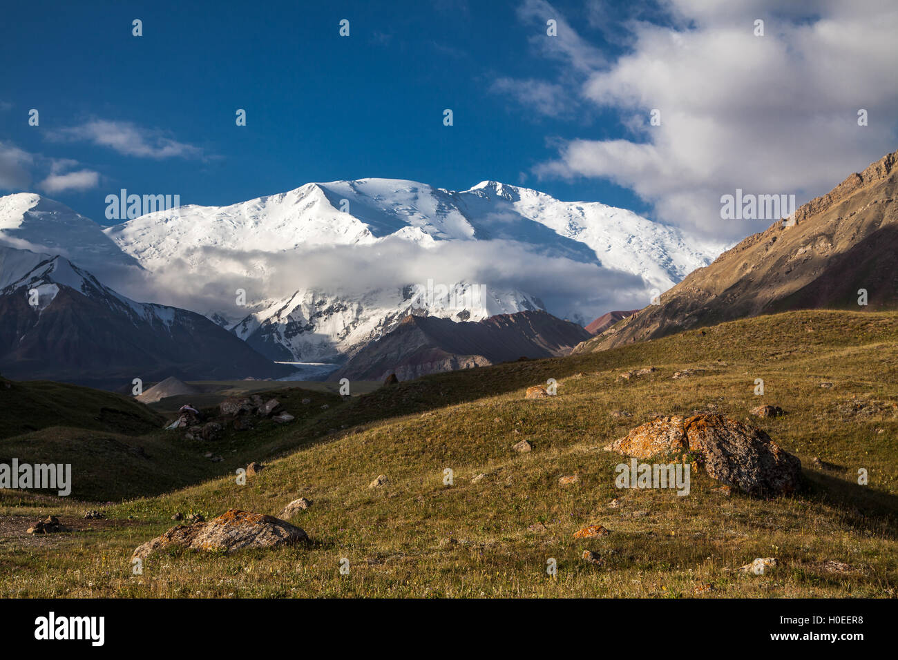 Rochers, l'herbe, et le sommet de la crête de Lénine. Vue du camp de base Achik-Tash. Région du Pamir. Kirghizistan Banque D'Images