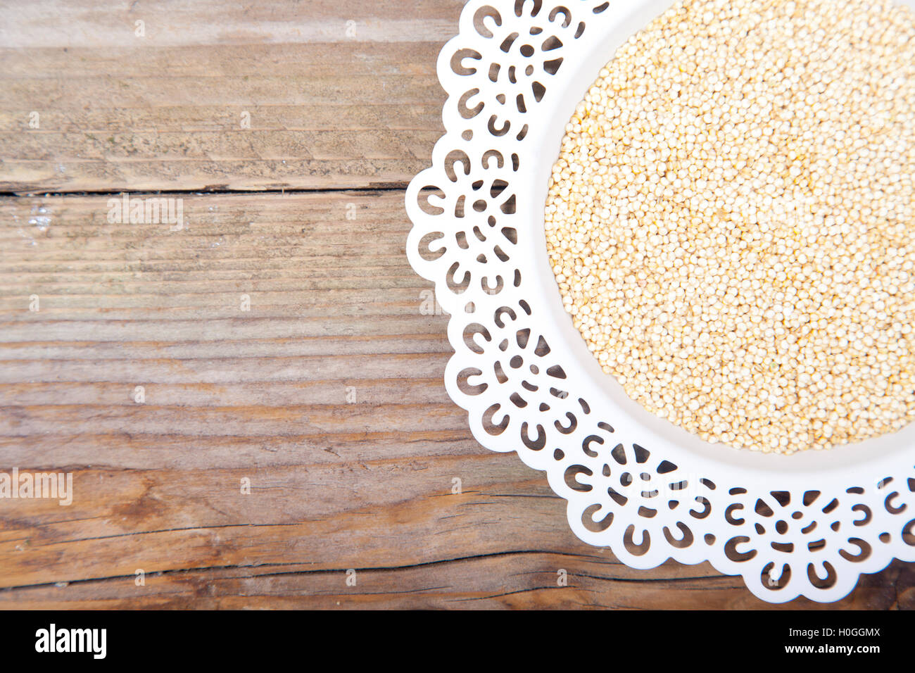 Le quinoa blanc sur plaque blanche sur fond de bois brun Banque D'Images