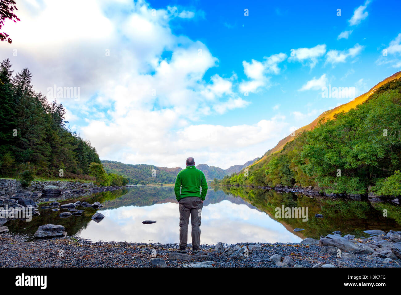 Une personne bénéficiant de la vue sur le lac ou Llyn Crafnant Crafnant que le soleil essaie de percer le jour de l'Équinoxe d'automne. L'heure et la date (deux fois par an) à laquelle le soleil traverse l'équateur céleste, lorsque le jour et la nuit sont de longueur égale. Banque D'Images