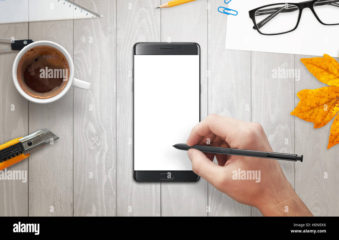 Homme écrit avec un crayon sur l'écran du téléphone. Smart phone moderne sur la table et un crayon dans la main. Pour affichage isolé immersive. Un café Banque D'Images