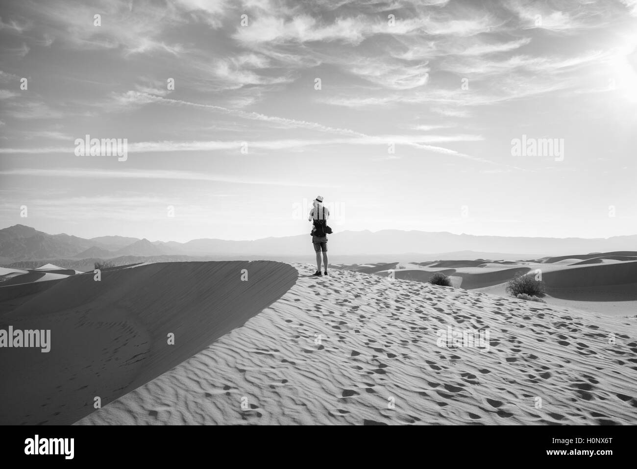 Young man photographing sand dunes, touristiques, de Mesquite Flat dunes de sable, Amargosa Range derrière, la vallée de la mort Banque D'Images