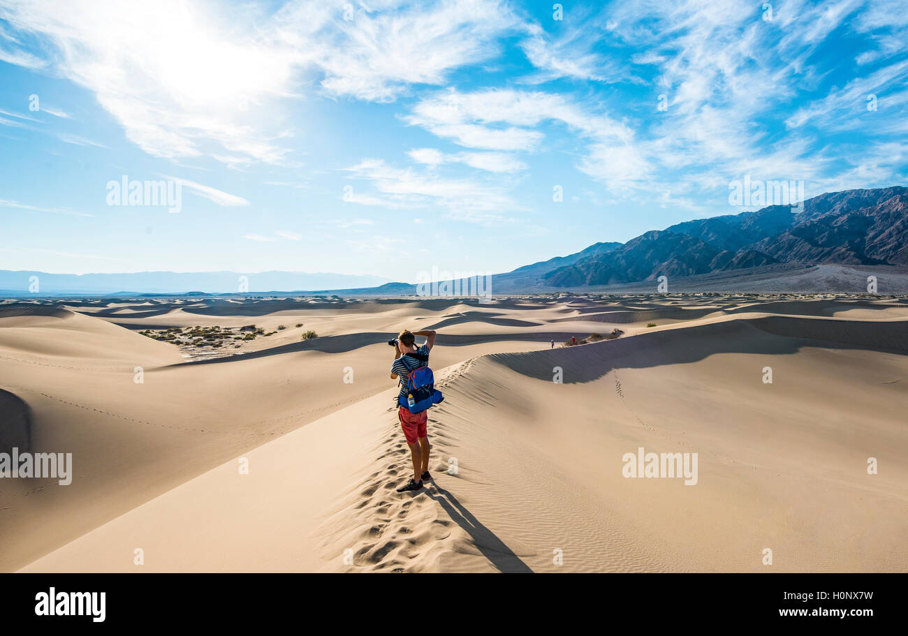 Young man photographing sand dunes, touristiques, de Mesquite Flat dunes de sable, contreforts de l'Amargosa Range derrière, la vallée de la mort Banque D'Images