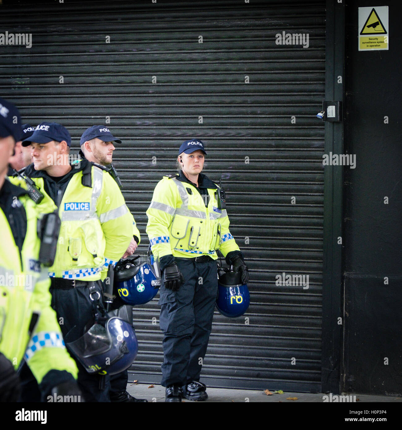 Blonde, femme agent de police, la caméra regarde nerveusement tandis qu'à devoir regarder Bristol Rovers football supporters Banque D'Images