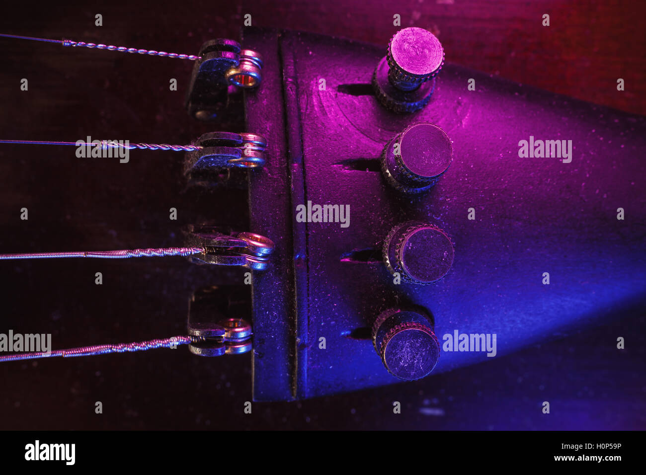 Studio de la composition d'un vieux violon poussiéreux, bleu et violet à partir de l'éclairage de côté, vue rapprochée sur fine tuners et des chaînes. Banque D'Images