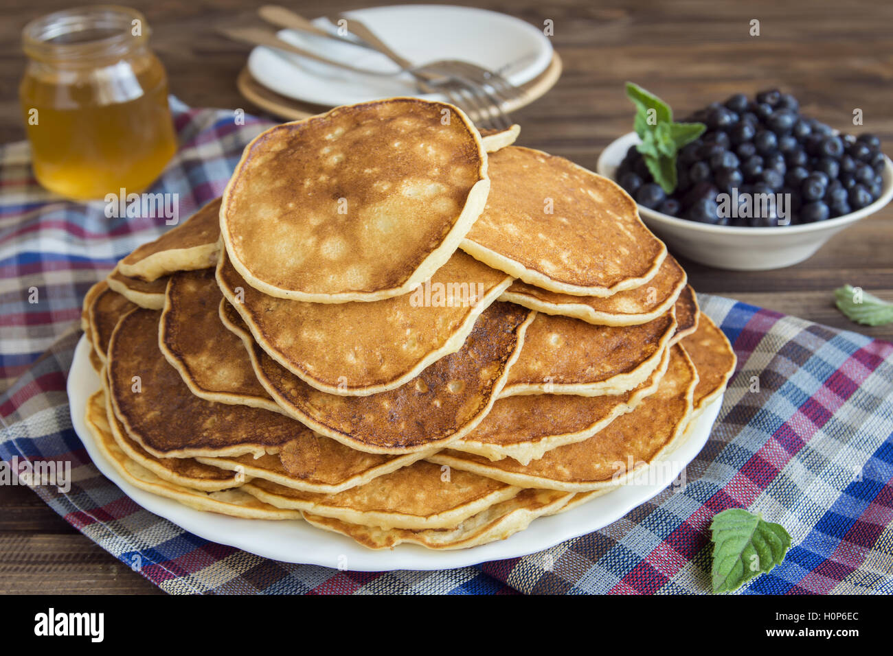 Des crêpes sur la plaque avec les bleuets et du miel pour déjeuner en famille - Nourriture végétarienne saine fait maison Banque D'Images