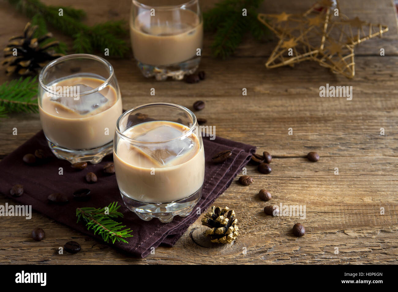 Irish Cream Liqueur de café avec de la glace, et des ornements de décoration de Noël sur fond de bois rustique - boisson festive fait maison Banque D'Images