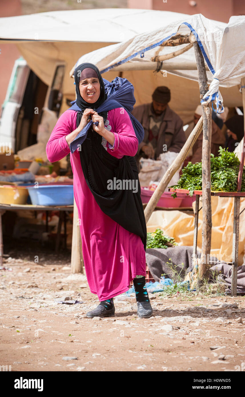 Montagnes de l'Atlas, au Maroc. Scène de marché dans Village près de gorges du Dadès. Femme berbère transporter ses achats sur son dos. Banque D'Images