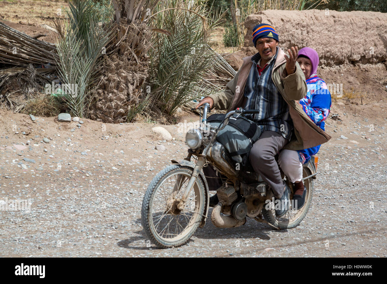 Skoura, Maroc. Middle-aged Couple marocain sur moto. Le geste signifie "What's up ?" Ou "Qu'est-ce que tu fais ?" Banque D'Images