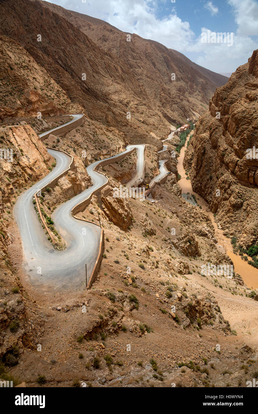 Les gorges du Dadès, au Maroc. Des virages en épingle sur la route à la sortie de la gorge. L'eau boueuse dans le flux de fortes pluies en amont. Banque D'Images