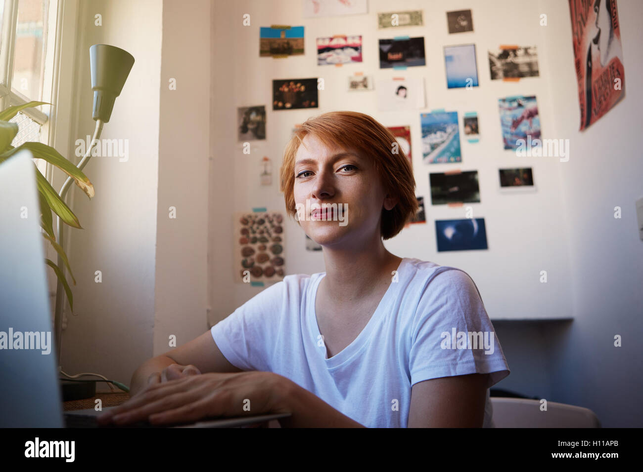 Une femme moderne au cours de processus de travail collaborateur Smiling.Jeune Hipster Projet de démarrage.femme cheveux courts et blanc tshirt tapant ordinateur lumière du matin. Concept d'emploi productif place confortable. Banque D'Images