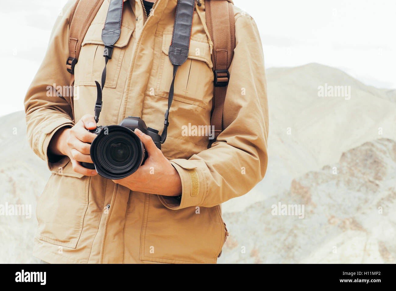 Close-up de journaliste photographe de voyage tenant un appareil photo DSLR en arrière-plan la montagne. Banque D'Images