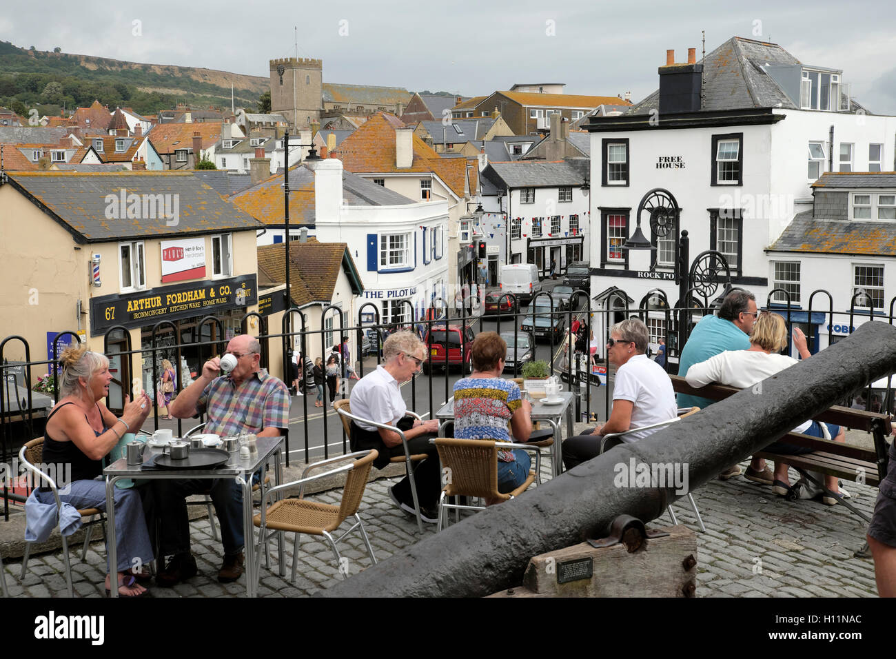 Les aînés des gens assis à des tables de boire du café et de manger des aliments à l'extérieur dans un café avec vue sur la ville de Lyme Regis, dans le Dorset en Angleterre KATHY DEWITT Banque D'Images