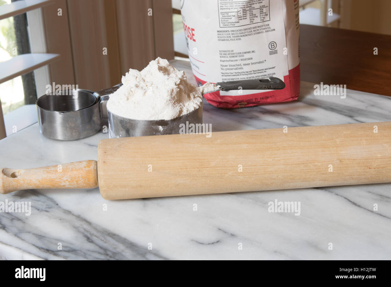 En table à pétrir avec la farine à pâtisserie mélange bol et rouleau à pâtisserie avec lumière naturelle d'une fenêtre Banque D'Images