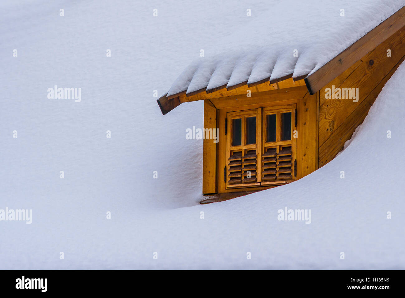 Lucarne sur un toit couvert de neige d'un bâtiment. Contraste de bois marron foncé de la lucarne et de la neige fraîche et blanche. Espace libre pour ent Banque D'Images