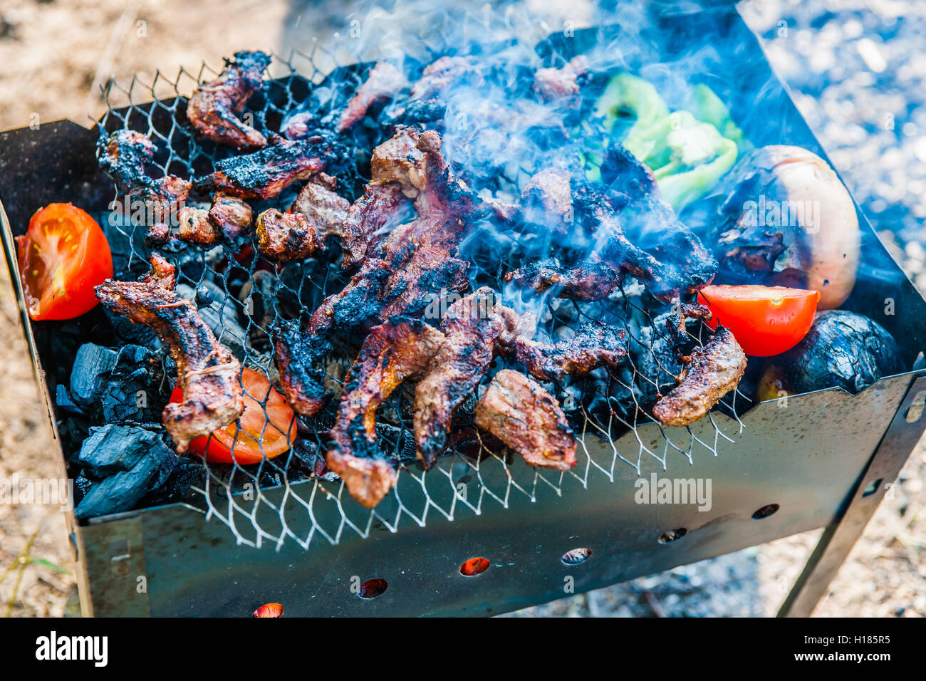 Barbecue - viande, tomates, poivrons fry sur une grille à l'extérieur. La nourriture pour un week-end picnick. Scène d'été. Banque D'Images