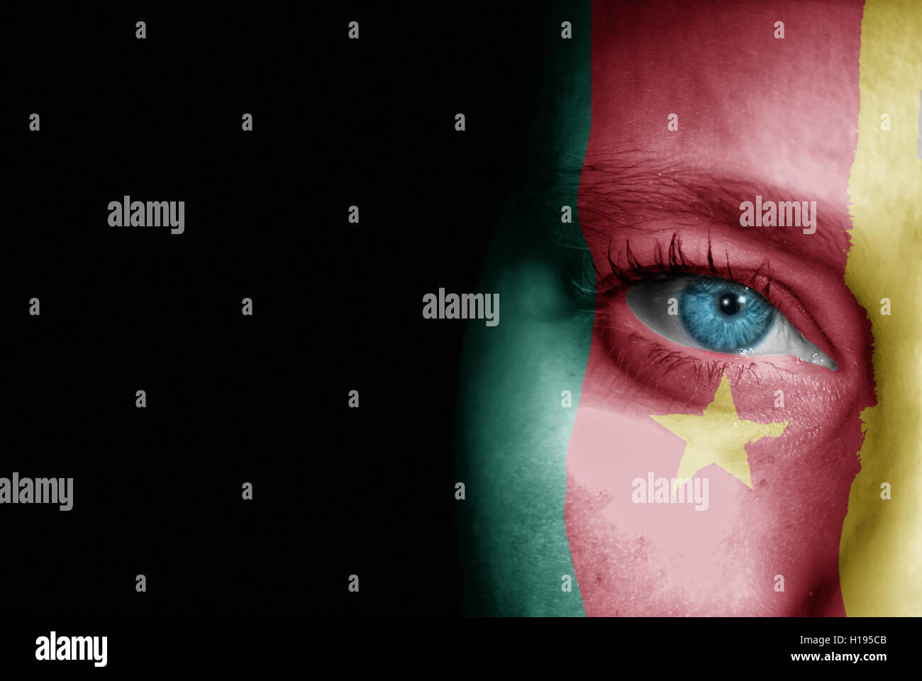 Une jeune femme avec le drapeau du Cameroun peint sur son visage sur son chemin à un événement sportif pour montrer son soutien. Banque D'Images