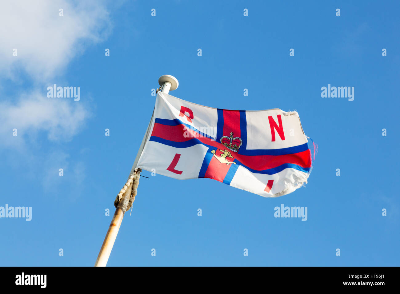 La RNLI (Royal National Lifeboat Institution ) flag flying sur un mât contre un ciel bleu, Norfolk, UK Banque D'Images