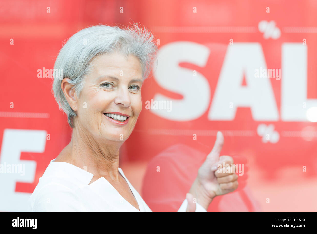 Senior woman in front of a sale sign Banque D'Images