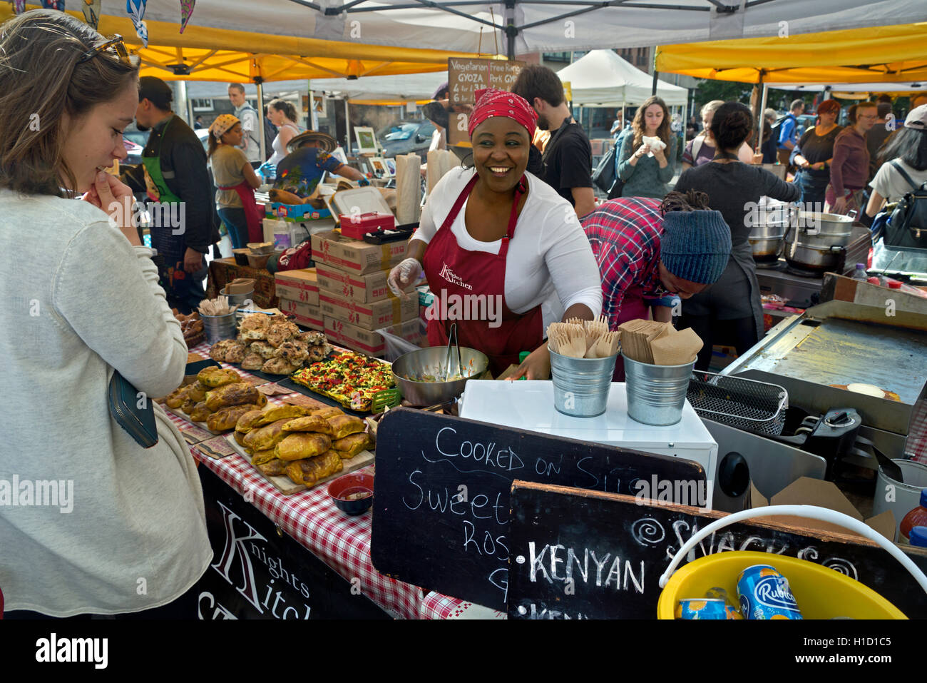 Un chef souriant servant une cuisine africaine sur un stand dans le marché du samedi à Grassmarket, Édimbourg, Écosse, Royaume-Uni. Banque D'Images