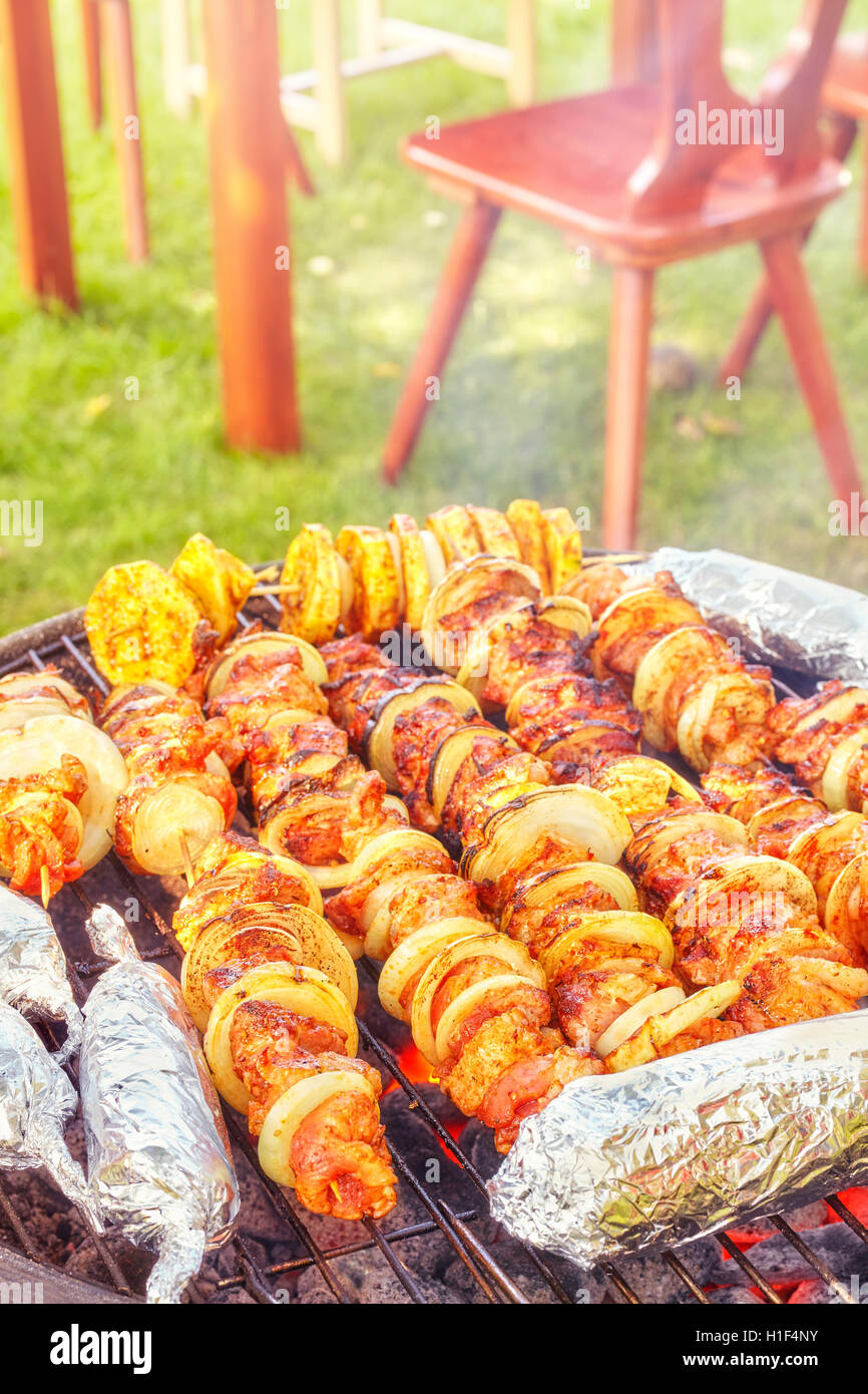Les brochettes de viande avec des oignons et des épis de maïs dans de l'aluminium, jardin barbecue, selective focus. Banque D'Images