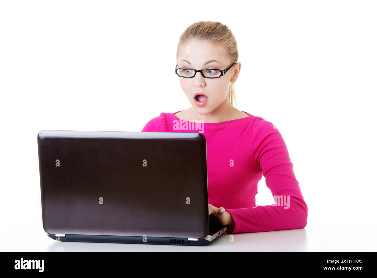 Les jeunes surpris femme assise en face de l'ordinateur portable. Banque D'Images