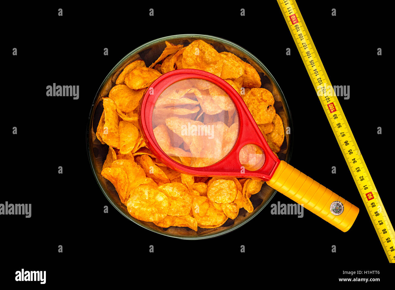 Un bol de croustilles de pommes de terre avec la loupe et règle de mesure, isolé sur Banque D'Images