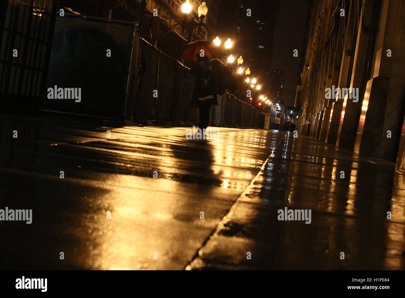 Silhouette de personne marchant sur les trottoirs de Chicago des pluies en soirée avec des réflexions sur sol mouillé Banque D'Images