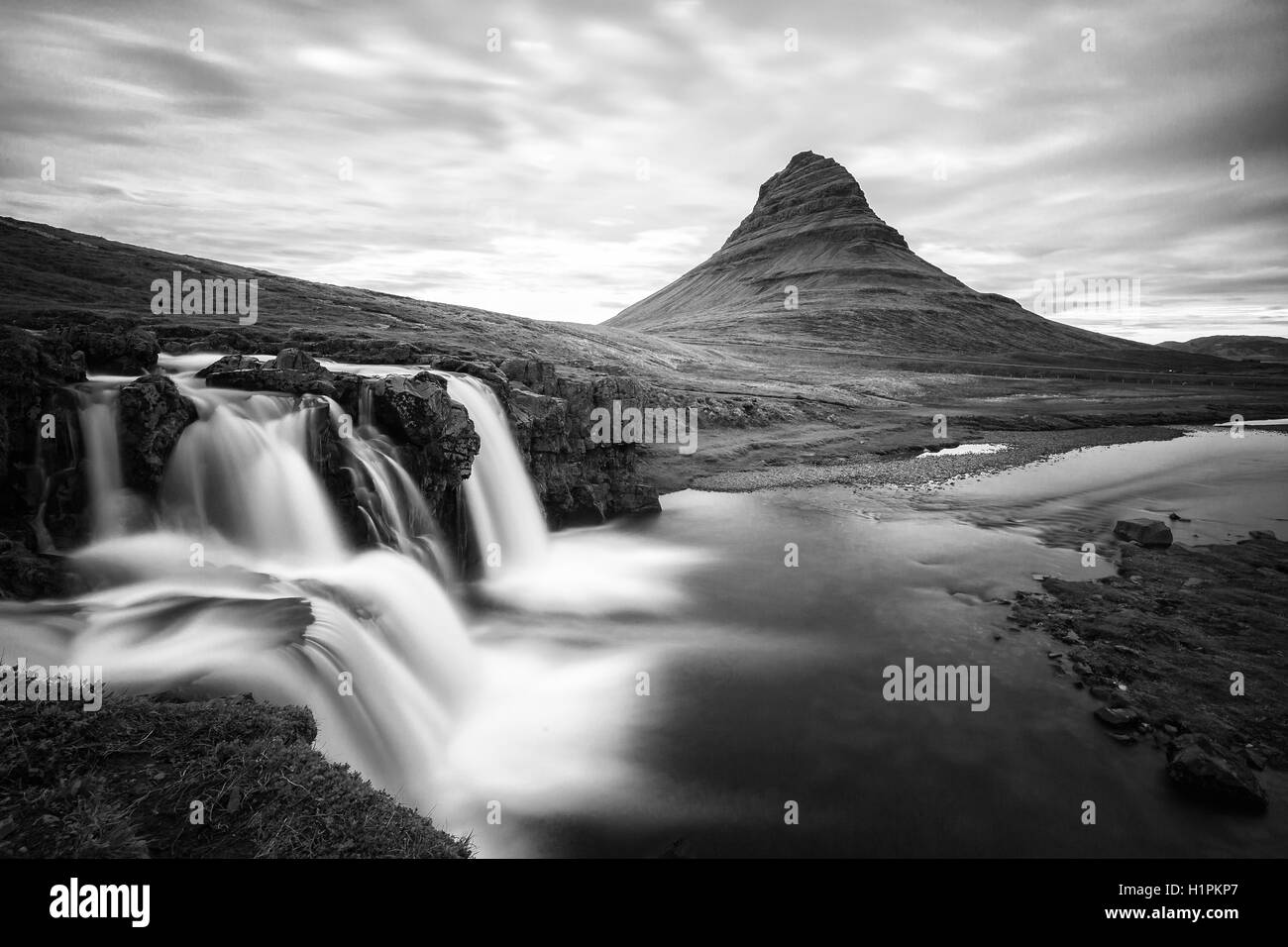 Incroyable coucher du soleil du haut de la chute d'Kirkjufellsfoss avec Kirkjufell mountain en arrière-plan sur la côte nord de l'Islande. Banque D'Images
