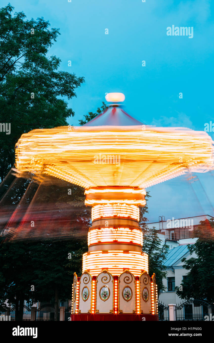 Effet de mouvement floue autour de éclairées Carrousel rotatif à grande vitesse Merry-Go-Round. Soir d'été en ville Amuseme Banque D'Images