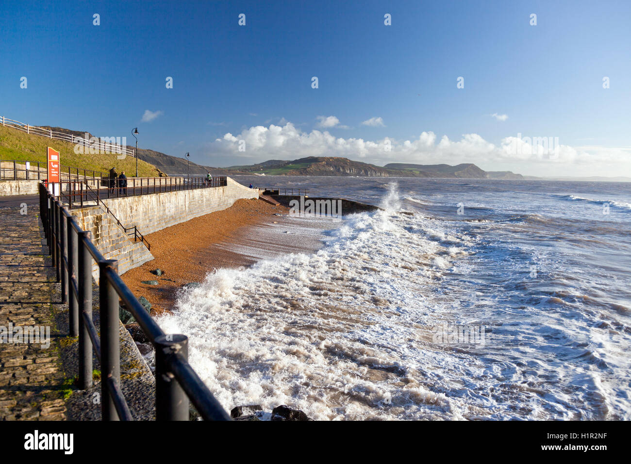 Les ondes de tempête écraser sur la plage et contre la nouvelle digue à Lyme Regis avec Golden Cap au-delà, Dorset, England, UK Banque D'Images