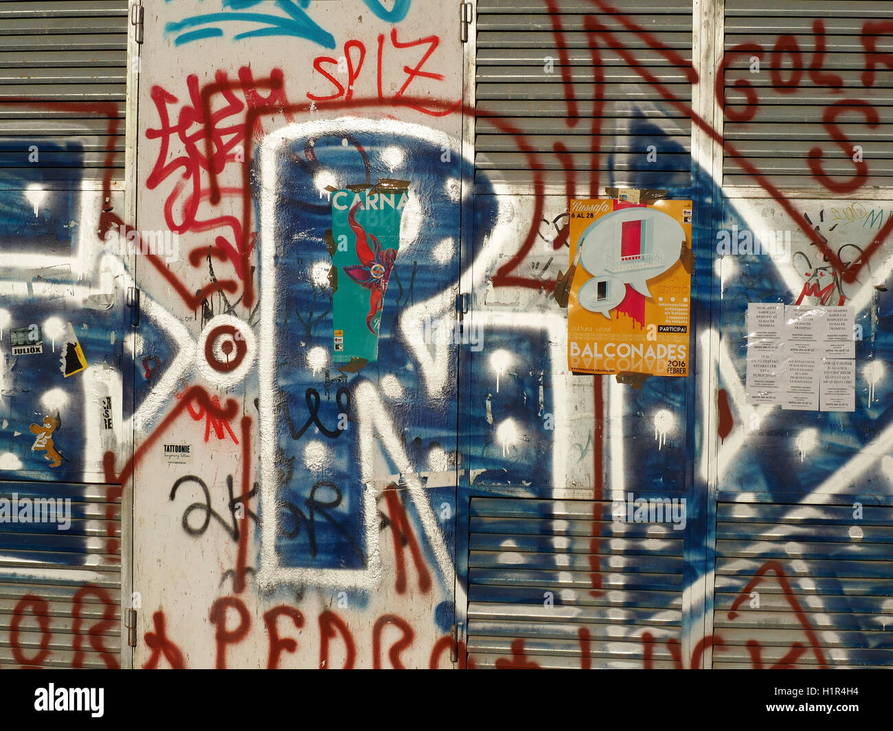 Rouge bleu et blanc peint des graffitis sur les volets métalliques gris gris et blanc mur allée à Valence Espagne Espana affiche jaune avec Banque D'Images