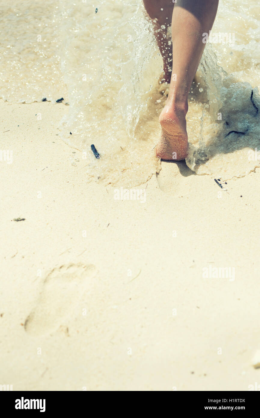 Femme marche sur la plage de sable en laissant des traces de pas dans le sable Banque D'Images