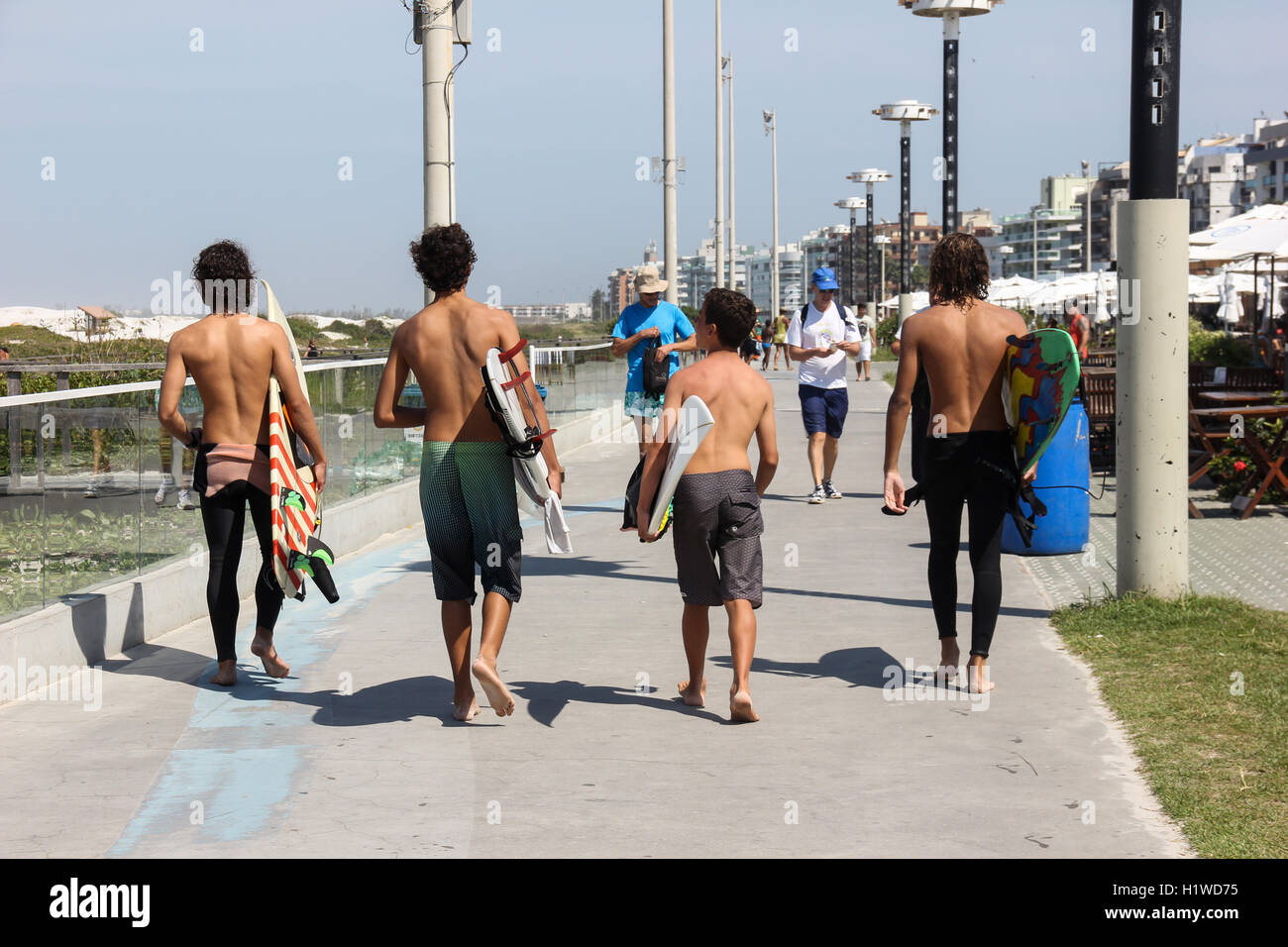 Avis de quatre jeunes hommes portant des planches sur le bord de la plage Praia do Forte dans la région de Cabo Frio, à Rio de Janeiro, Brésil. Ils vont Banque D'Images